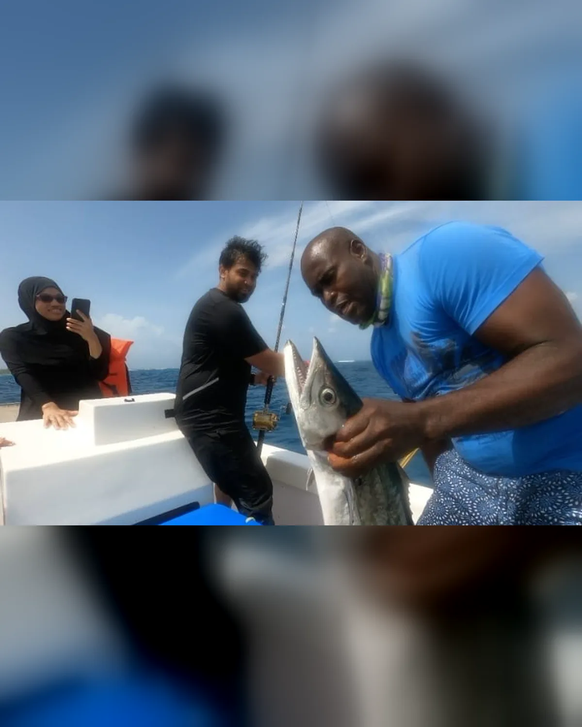 Guests aboard watching a kingfish come in, one filming on her phone