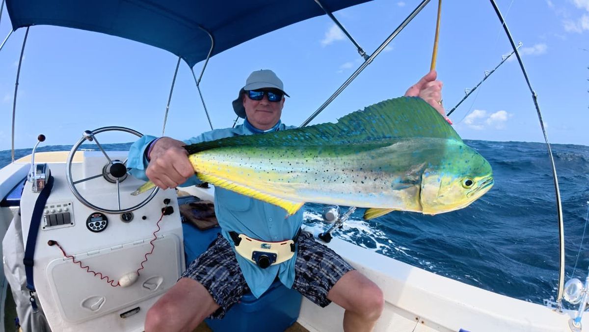 A guest holding a bull mahi mahi on deck