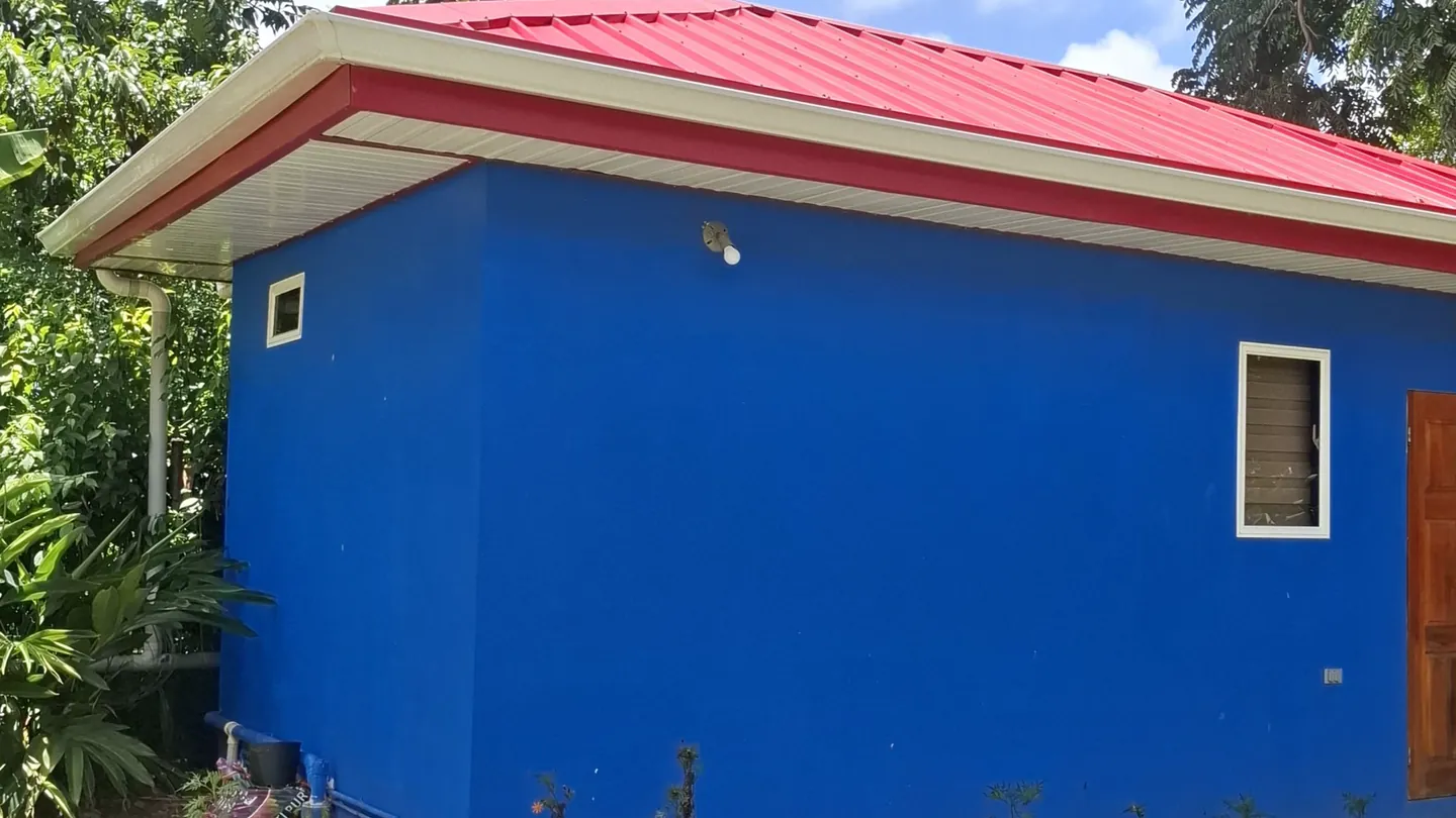 The Mango Room's freestanding blue cabin with its red roof, in the garden