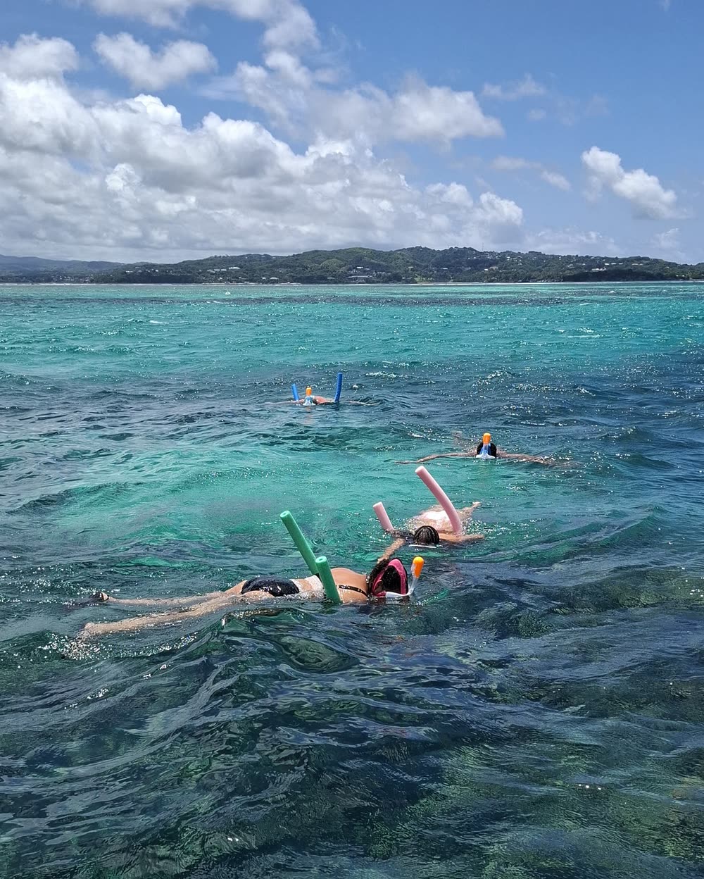 Snorkellers strung out across the shallow flats with floats, the headland in the distance