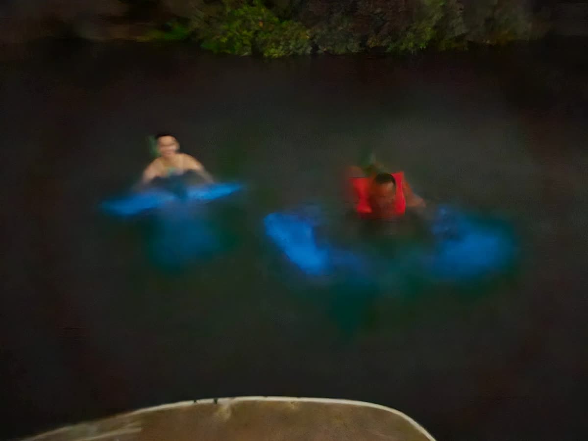 Two swimmers in the lagoon, each ringed by a patch of blue glow