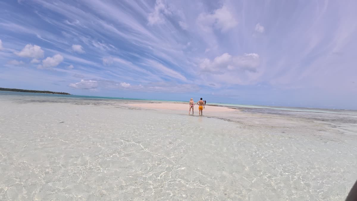 Two guests standing on the Nylon Pool sandbank, waist-deep in clear water in the middle of the sea